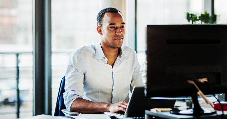 man sits at desk and uses computer