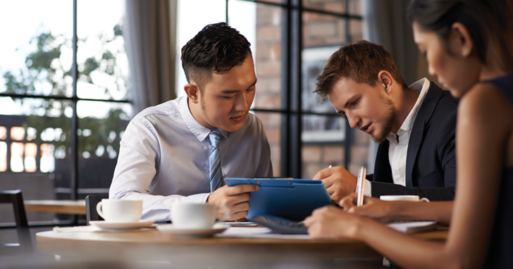 Couple talks with their financial advisor while reviewing paperwork