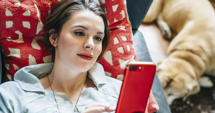 Woman lying down and looking at her iPhone